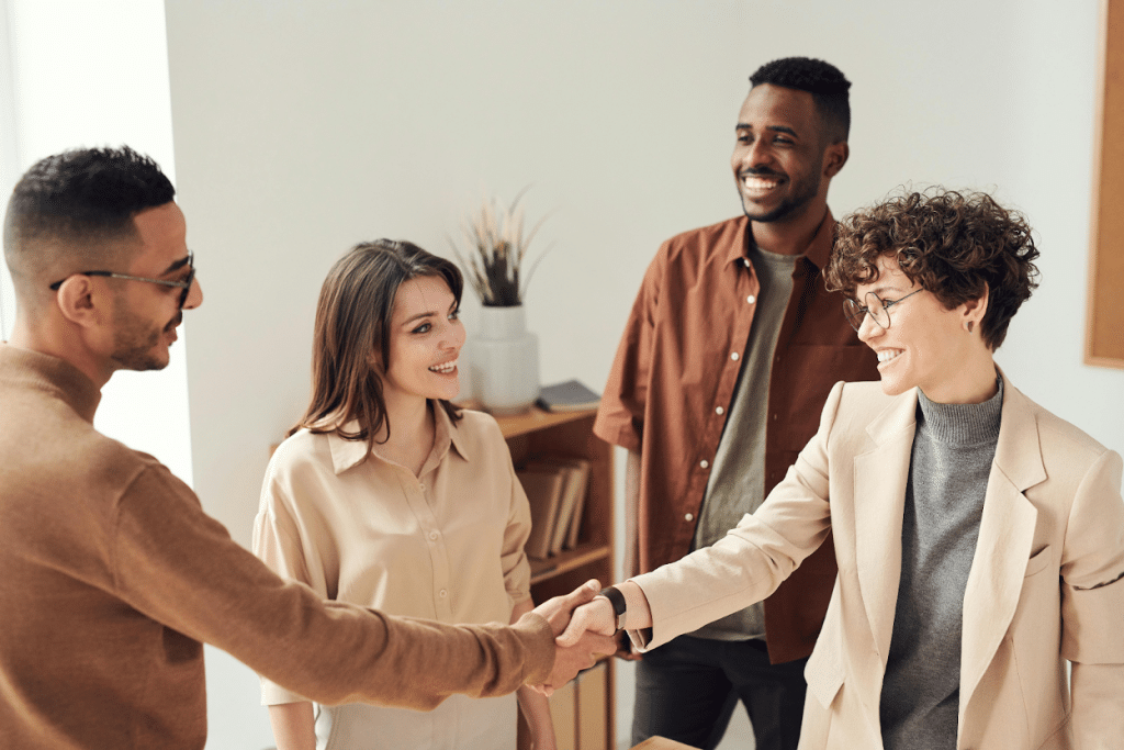 Commercial vs Consumer Collections: Differences & Examples 5 Business professionals shaking hands in an office setting