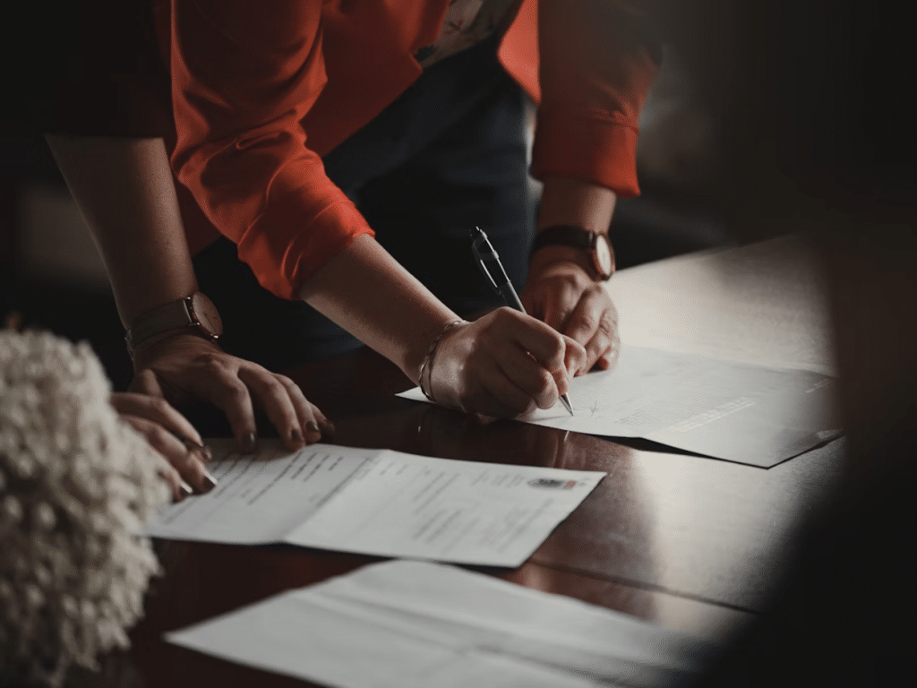 How Much Does it Cost to Send Someone to Collections: Agency Fees Explained 3 Business professionals signing documents at a desk