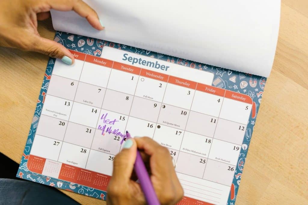 Sending Unpaid Rent to Collections: Steps & Laws Explained 3 Person checking and marking payment dates on a calendar