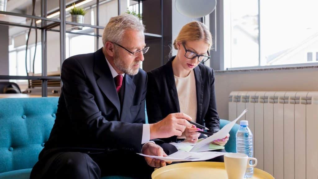 Debt Settlement vs Debt Collection: Cost & Differences Explained 4 Business meeting with two professionals reviewing settlement documents and contracts.