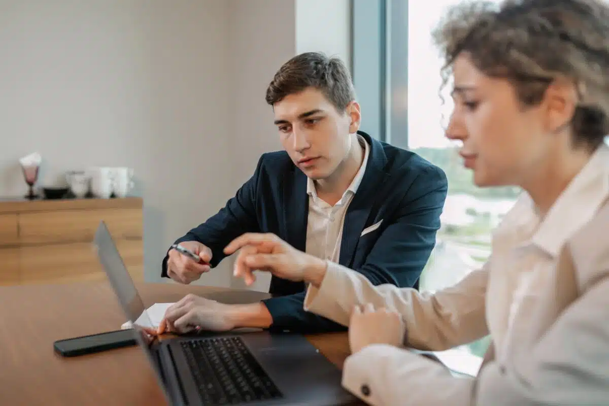 Accounts Receivable Agency: Services, Fees & Best Options 3 Two business professionals review information together on a laptop at a wooden table.
