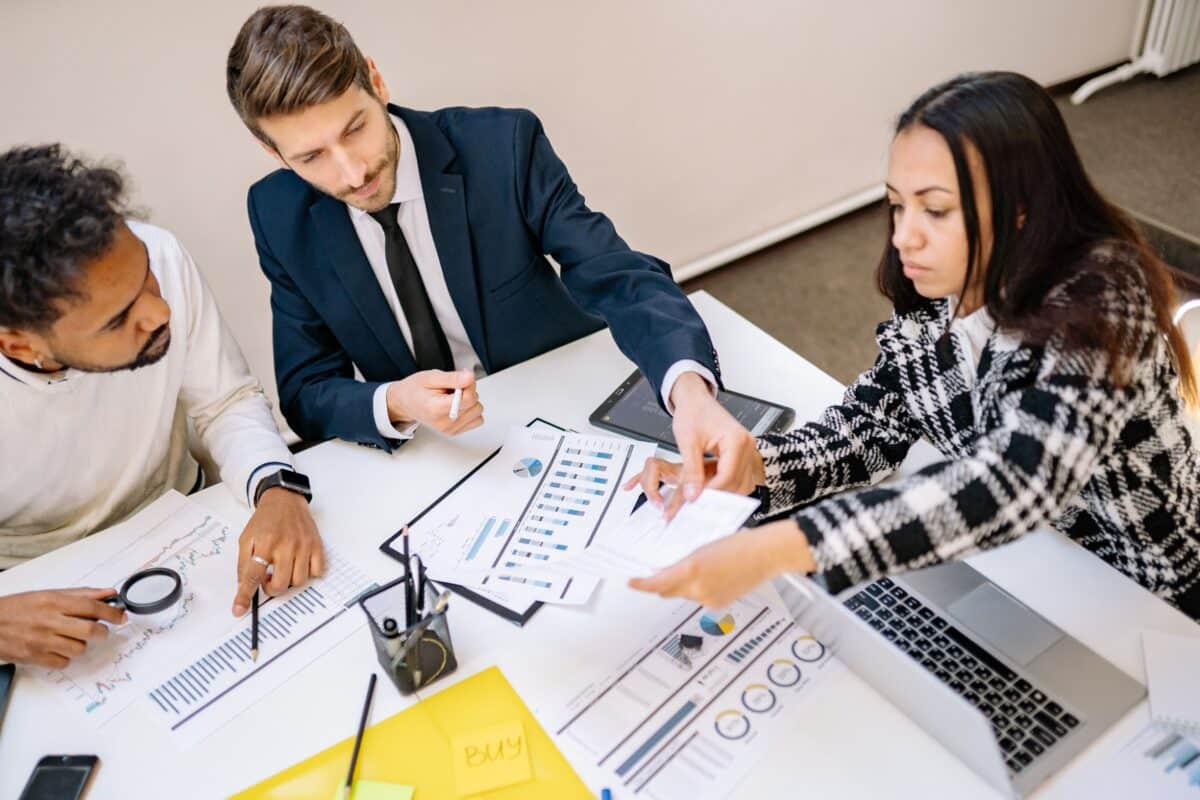 Accounts Receivable Risk Management: Examples & Solutions 3 Three colleagues analyze financial charts and reports together at an office desk with a laptop.