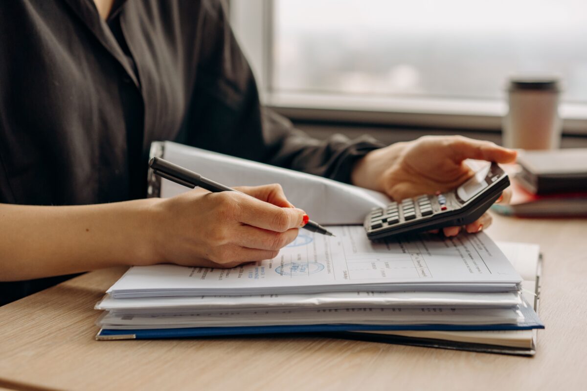 Accounts Receivable vs Debt Collection: Key Differences 4 A woman reviewing stamped financial documents while operating a calculator at a desk