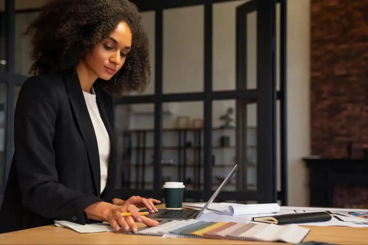 Final Demand Letter Before Legal Action: Samples, Timing & Options 4 A person drafting a formal business letter at a desk with printed invoices, a pen, and a laptop.